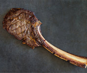 Whole cooked tomahawk steak with a dark seared crust